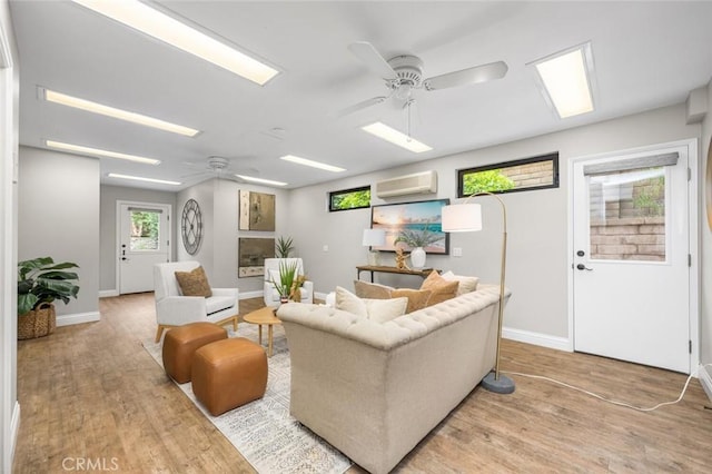 living room featuring wood finished floors, an AC wall unit, and ceiling fan