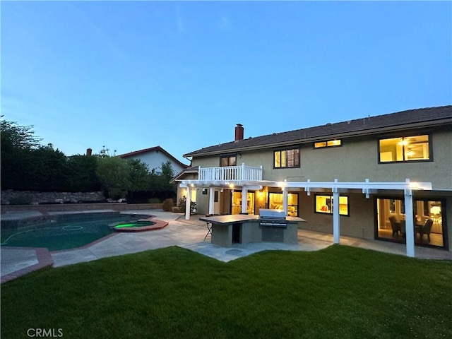 rear view of house featuring a patio area, a yard, exterior kitchen, and stucco siding