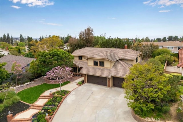 view of front of home with a tile roof, driveway, a chimney, an attached garage, and stucco siding