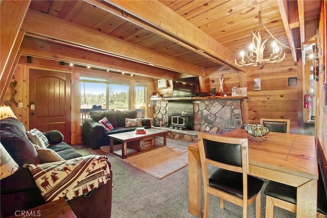 carpeted living room featuring wood ceiling, wood walls, a fireplace, and a notable chandelier