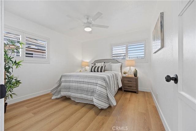 bedroom with baseboards, multiple windows, and light wood-style flooring