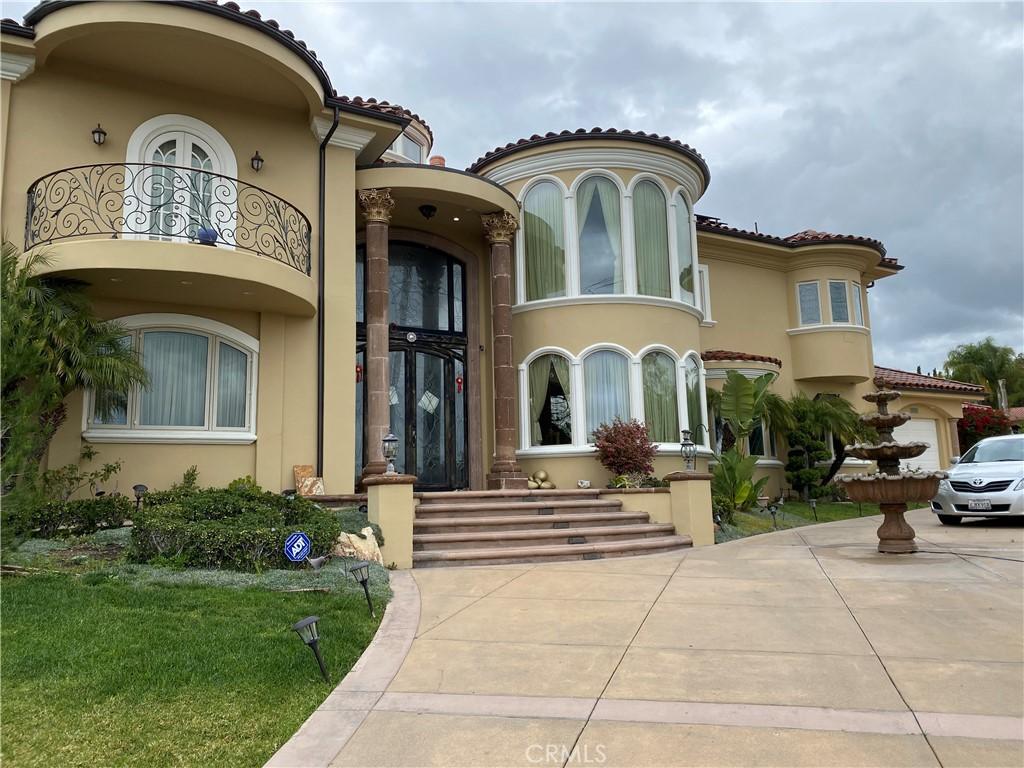 doorway to property featuring stucco siding, a tile roof, concrete driveway, and a balcony
