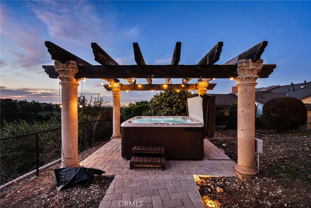 patio terrace at dusk featuring fence, a hot tub, and a pergola