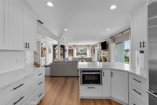27361 Rainbow Ridge Rd, Palos Verdes Peninsula, CA 90274 - kitchen with white cabinets, backsplash, recessed lighting, a peninsula, and stainless steel oven