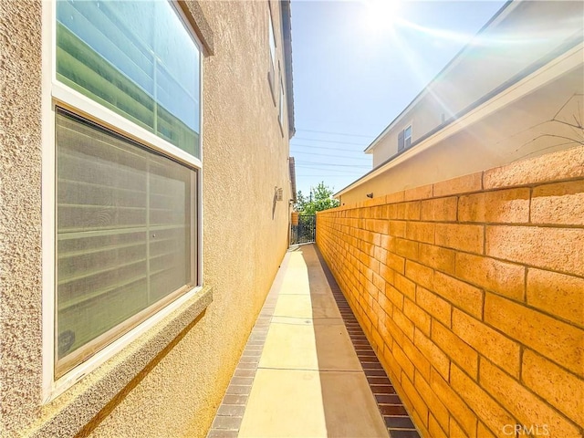 view of side of home with stucco siding and fence