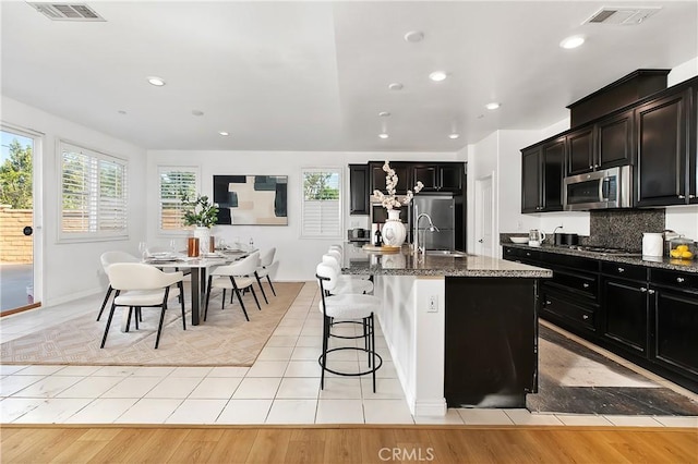 kitchen with dark stone countertops, a wealth of natural light, visible vents, and stainless steel appliances