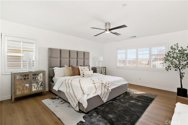 bedroom featuring baseboards, visible vents, wood finished floors, and ceiling fan