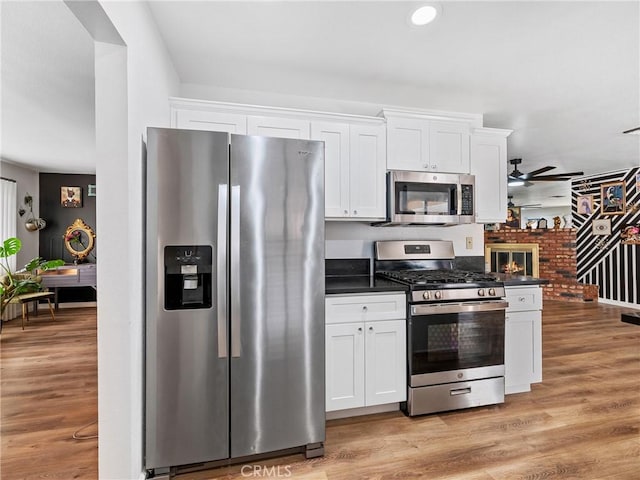 904 Pinon Dr, Barstow, CA 92311 - kitchen featuring appliances with stainless steel finishes, dark countertops, ceiling fan, white cabinetry, and light wood finished floors