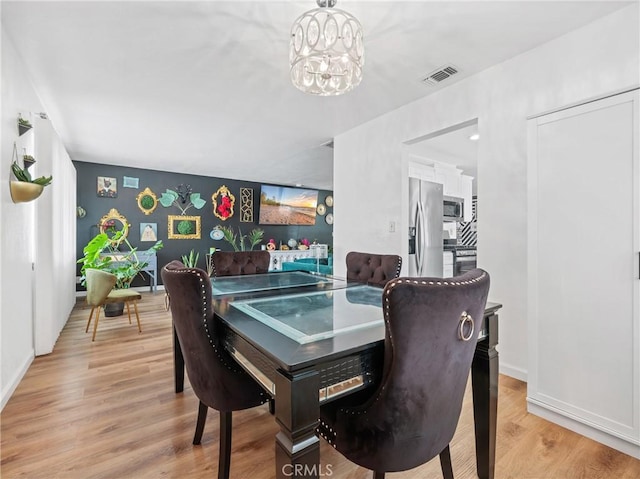 904 Pinon Dr, Barstow, CA 92311 - dining room with a chandelier, light wood-style floors, baseboards, and an accent wall