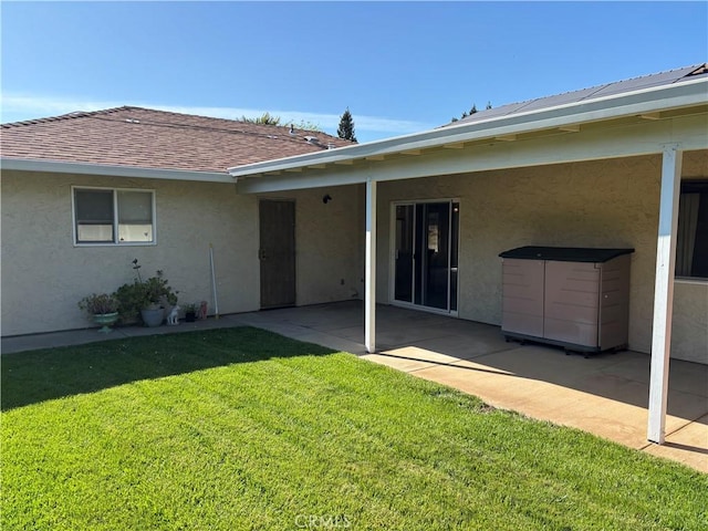 back of property featuring a yard, a patio, and stucco siding