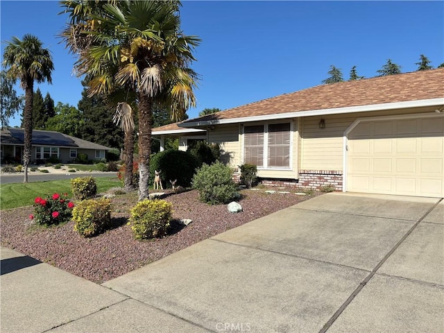 single story home with a garage, driveway, and brick siding