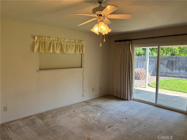 carpeted empty room featuring ceiling fan and baseboards