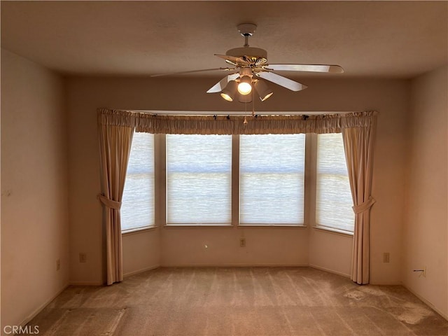 spare room with light carpet, a wealth of natural light, and ceiling fan