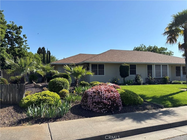 ranch-style house featuring a front yard and fence