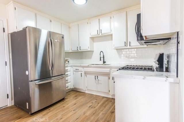 9213 Jacaranda Ave, California City, CA 93505 - kitchen with freestanding refrigerator, stove, light wood-style flooring, decorative backsplash, and white cabinets
