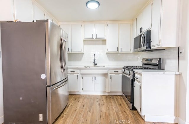 9213 Jacaranda Ave, California City, CA 93505 - kitchen with stainless steel appliances, light countertops, backsplash, light wood-type flooring, and white cabinets
