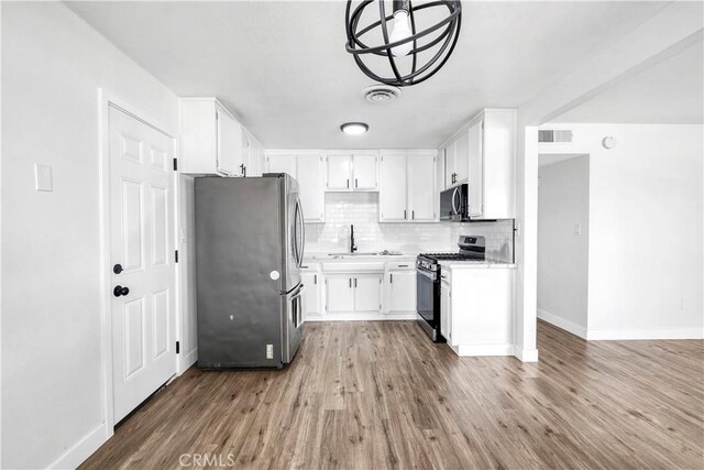 9213 Jacaranda Ave, California City, CA 93505 - kitchen featuring appliances with stainless steel finishes, wood finished floors, light countertops, backsplash, and white cabinetry