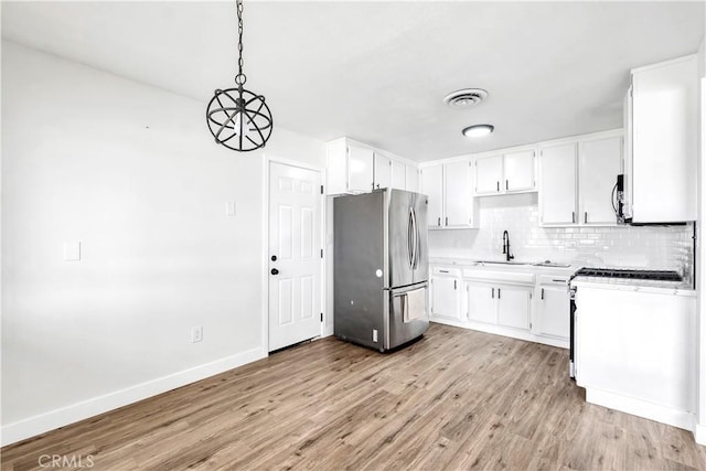 9213 Jacaranda Ave, California City, CA 93505 - kitchen with appliances with stainless steel finishes, light wood-style floors, tasteful backsplash, white cabinets, and light countertops