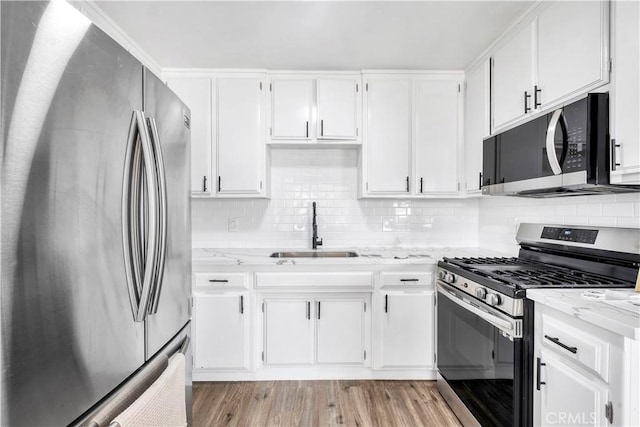 9213 Jacaranda Ave, California City, CA 93505 - kitchen featuring appliances with stainless steel finishes, white cabinetry, decorative backsplash, and light stone counters