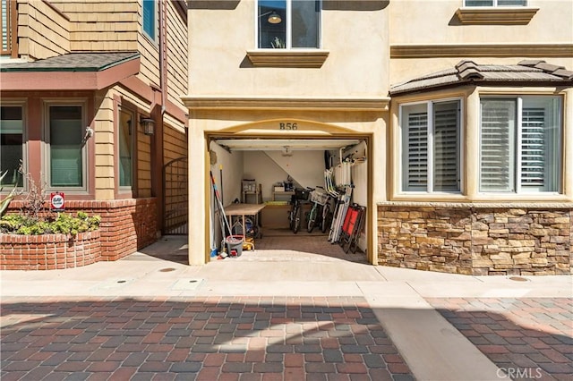 56 B Surfside Ave, Surfside, CA 90743 - doorway to property featuring an attached garage, stone siding, and stucco siding