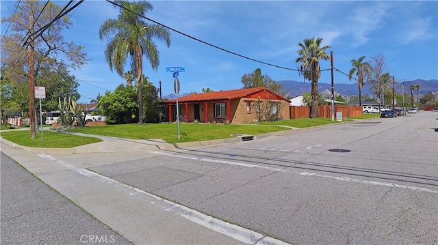 view of front of property featuring a tiled roof, a front yard, and a mountain view
