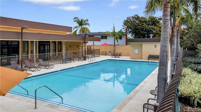 community pool with fence and a patio area
