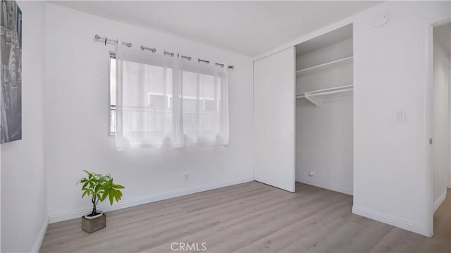 unfurnished bedroom with wood finished floors, a closet, and baseboards