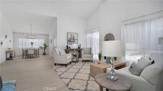 living room featuring an inviting chandelier, wood finished floors, and high vaulted ceiling