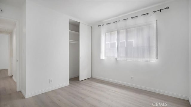unfurnished bedroom with wood finished floors, a closet, and baseboards