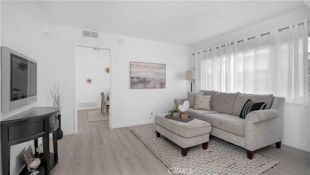 living area featuring visible vents, light wood-type flooring, and baseboards