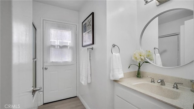 bathroom with wood finished floors, vanity, and baseboards