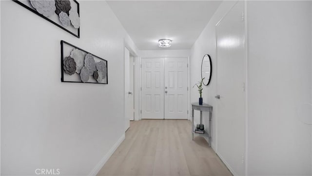 corridor with light wood finished floors and baseboards
