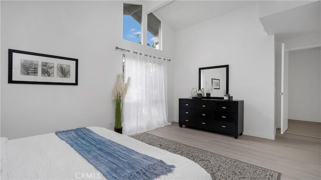 bedroom featuring high vaulted ceiling, wood finished floors, and baseboards