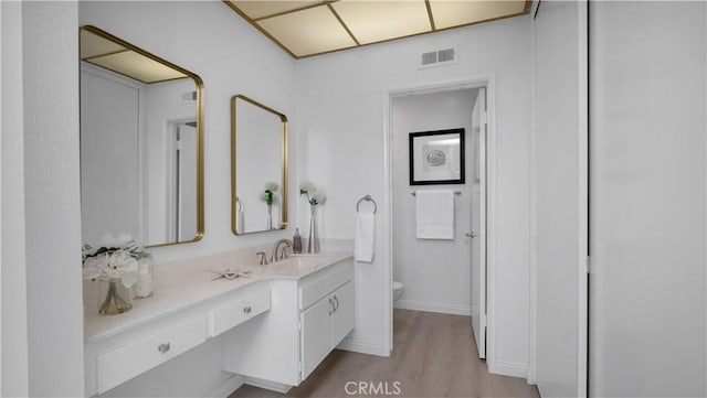bathroom with visible vents, baseboards, toilet, wood finished floors, and vanity