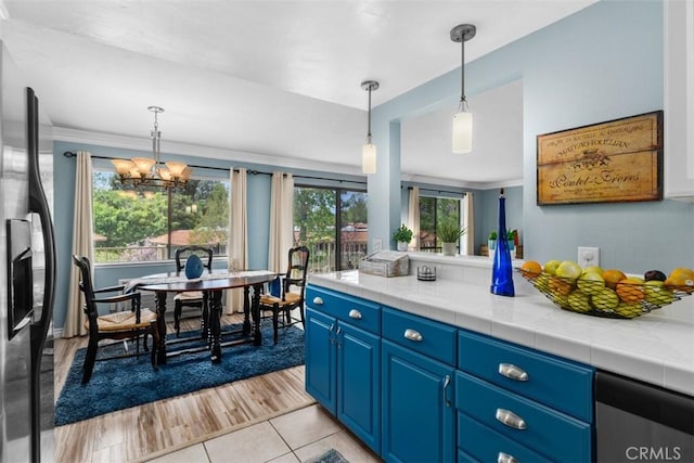 888 Ronda Sevilla Unit D, Laguna Woods, CA 92637 - kitchen with blue cabinets, an inviting chandelier, black fridge with ice dispenser, decorative light fixtures, and tile countertops