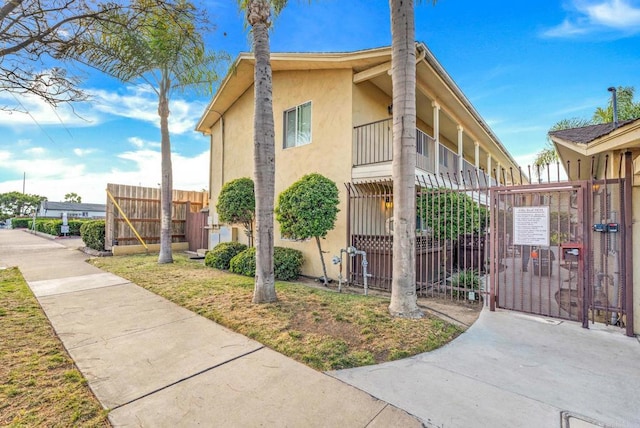 905 E 4th Ave Unit 1, National City, CA 91950 - view of side of home with fence, a gate, stucco siding, and a balcony