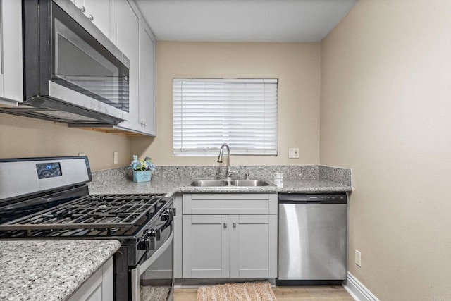 905 E 4th Ave Unit 1, National City, CA 91950 - kitchen with light wood-type flooring, a sink, appliances with stainless steel finishes, and light stone counters