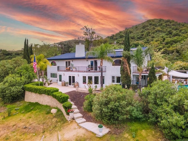 22053 Highland St, Wildomar, CA 92595 - rear view of house with a chimney, a patio area, a balcony, stucco siding, and a mountain view