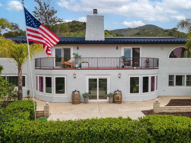 22053 Highland St, Wildomar, CA 92595 - rear view of house with a balcony, a chimney, stucco siding, and metal roof