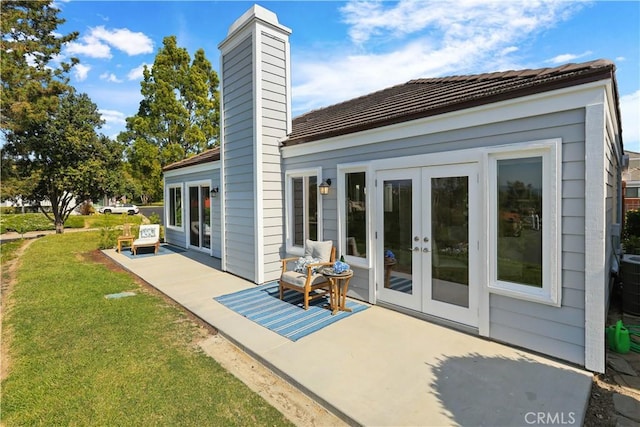 back of house featuring a lawn, a chimney, a patio, and french doors