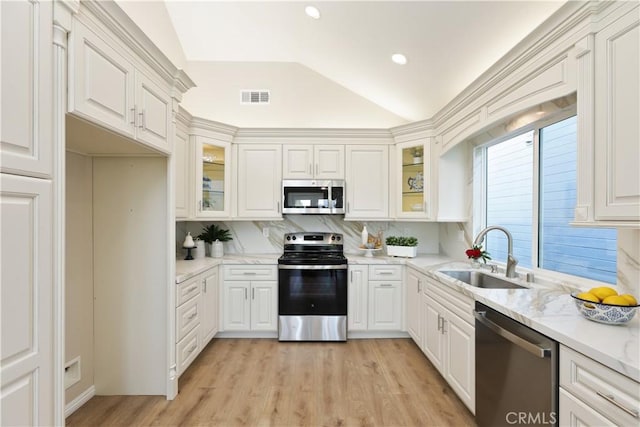 kitchen with tasteful backsplash, stainless steel appliances, vaulted ceiling, a sink, and visible vents