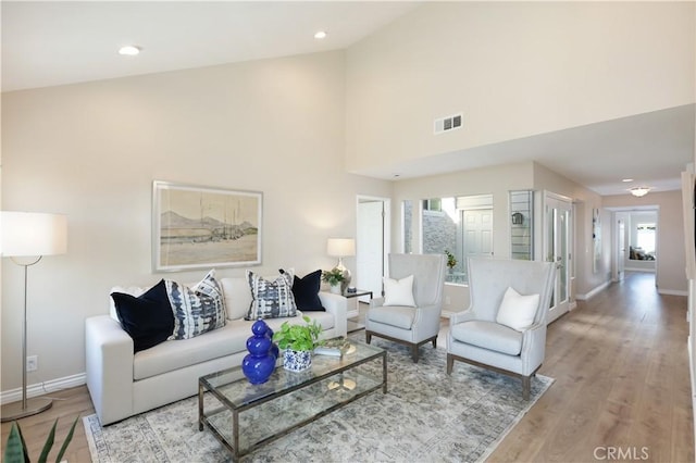 living area with a wealth of natural light, visible vents, light wood-style flooring, and baseboards