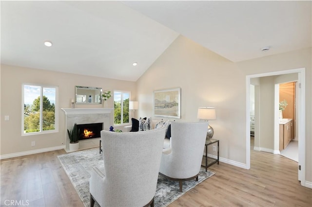 living room with light wood finished floors, baseboards, lofted ceiling, and a fireplace