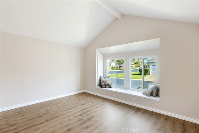 interior space featuring wood finished floors, vaulted ceiling with beams, and baseboards