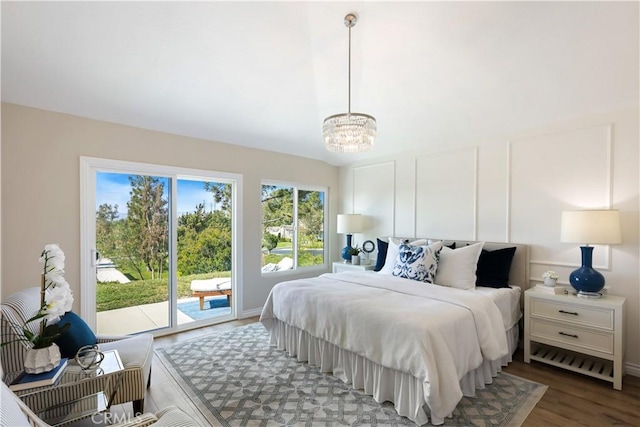 bedroom with access to exterior, an inviting chandelier, and wood finished floors