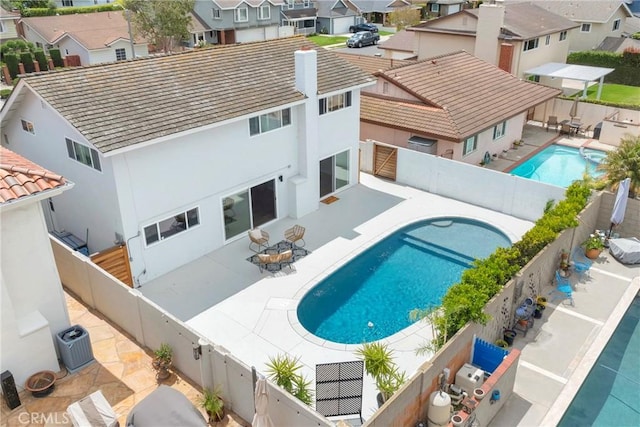 view of swimming pool with a fenced backyard, a residential view, a patio area, and central AC unit