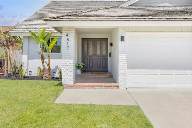 view of exterior entry featuring a yard, brick siding, and an attached garage