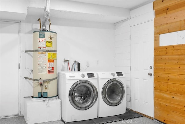 clothes washing area with strapped water heater and washing machine and dryer