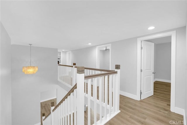 hallway with an upstairs landing, wood finished floors, baseboards, recessed lighting, and a chandelier
