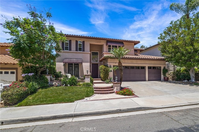 mediterranean / spanish house with a garage, a tile roof, driveway, and stucco siding